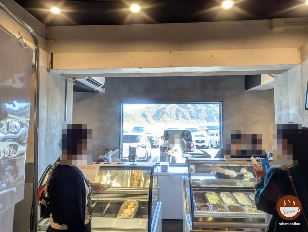 日本 熊本縣阿蘇市 ニュー草千里 ASO MILK ice cream shop:店裡的冰淇淋櫃台,窗外就是停車場和山